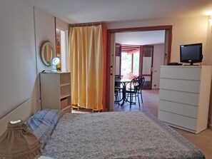 A room with a bed, a desk with a computer, a wardrobe, and a dining area with chairs and a table. - Beautiful  villa for 4 people with A/C, WIFI, TV, terrace and pets allowed (Sperlonga)