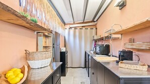 Une cuisine compacte équipée d’un réfrigérateur, d’un four à micro-ondes, d’un évier et d’étagères en bois.