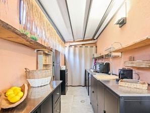 Eine kleine Küche mit Kühlschrank, Mikrowelle, Spüle und Holzregalen.