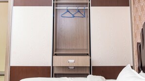 Ein Hotelzimmer mit Bett, Kleiderschrank und kleinem Schreibtisch.