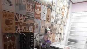 Cocina con salpicadero de azulejos, carteles relacionados con bebidas, encimera negra y un lavamanos.