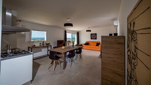 Een moderne keuken met een eethoek, uitzicht door het raam en een oranje bank in de woonkamer.