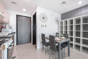 Una cocina moderna con estufa integrada, zona de comedor con mesa y sillas, y estantería fijada a la pared.