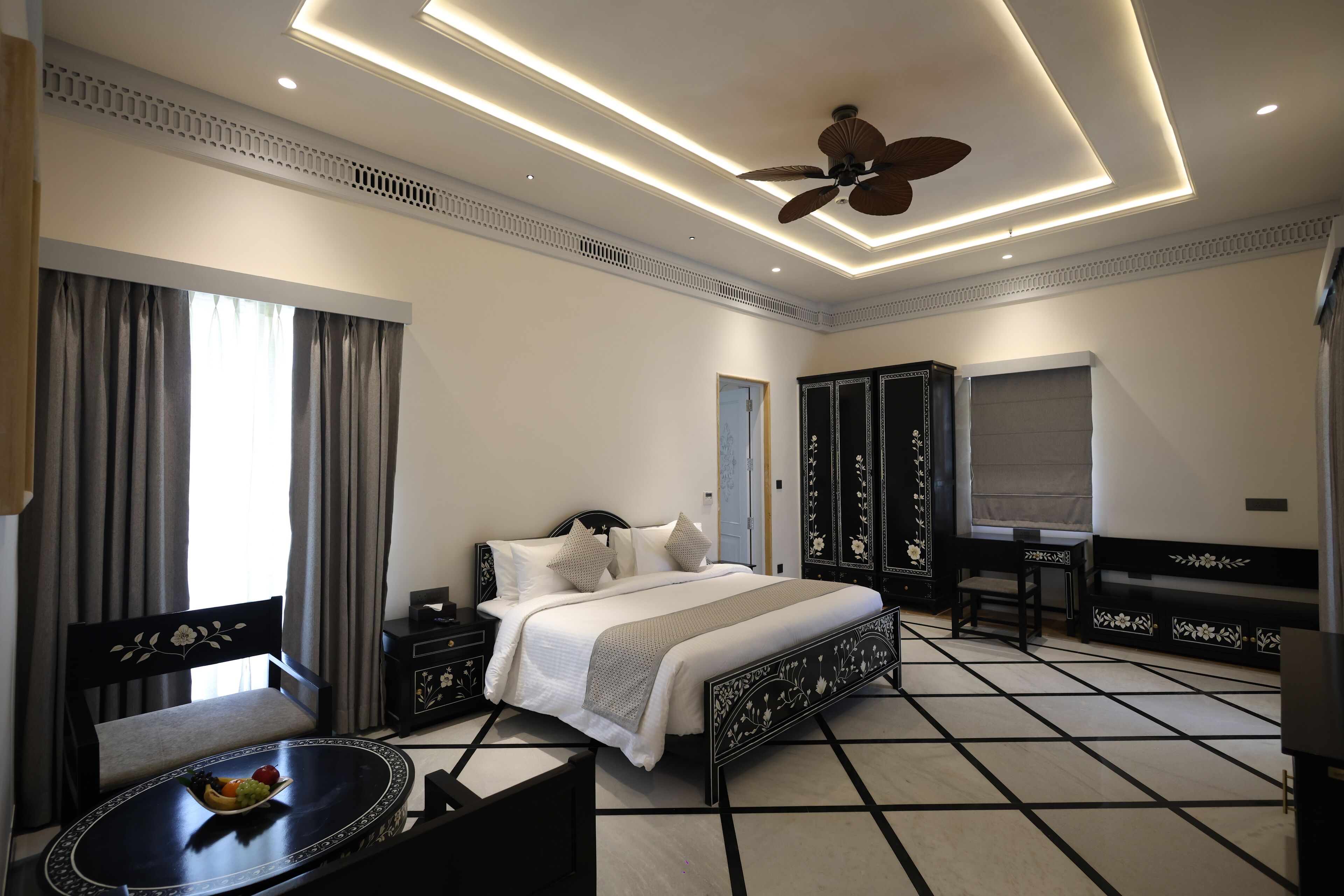 A modern hotel room with a bed, bedside tables, a desk, and a ceiling fan.
