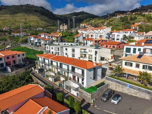 A residential area with modern houses, a parking area, and a hill in the background. - Andrade's Villa by HRM (Santa Cruz)