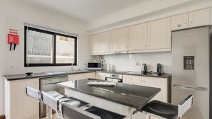 A modern kitchen with white cabinets, a stainless steel refrigerator, a microwave, and a dishwasher. - Andrade's Villa by HRM (Santa Cruz)