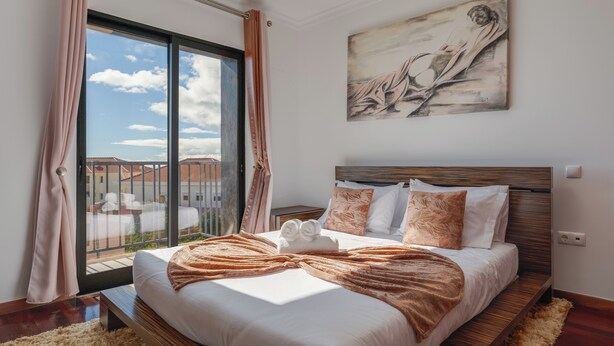 A modern bedroom with a large bed, a view through a sliding door, and a painting on the wall. - Andrade's Villa by HRM (Santa Cruz)
