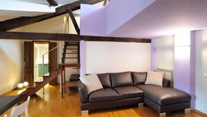 Un salon moderne avec un canapé en cuir marron, un plancher en bois et des poutres apparentes.