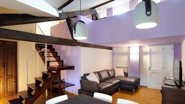 Un espace de vie moderne avec un escalier, un canapé en cuir et des luminaires suspendus.