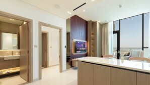 Ein modernes Hotelzimmer mit großem Fenster, einer zentralen Insellösung und einem separaten Badezimmerbereich.