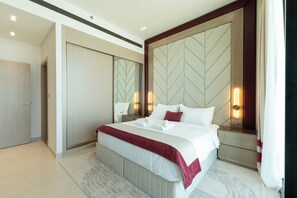 A modern hotel room with a large bed, a mirror, and a nightstand. - Exclusive High-Floor Apartment  (Dubai)