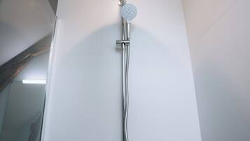 Une douche équipée d’un pommeau de douche à main et d’un robinet fixé au mur.