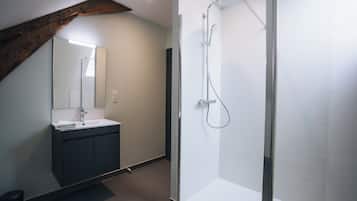 Une salle de bain moderne avec une douche à parois de verre, un lavabo avec un miroir et un meuble-lavabo aux tons foncés.