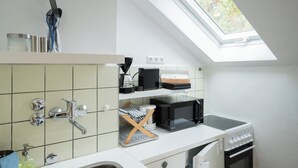 A compact kitchen with a skylight, a microwave, a kettle, and a stove. - Guesthouse Elena Apartment 21 (Kassel)