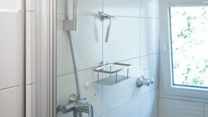 A shower with a handheld showerhead, a wall-mounted faucet, and a glass shelf. - Guesthouse Elena Apartment 21 (Kassel)