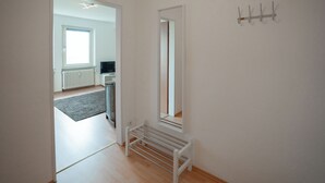 A hallway with a bench, a coat rack, and a mirror. - Guesthouse Elena Apartment 21 (Kassel)