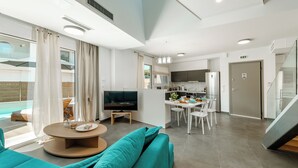 Una sala de estar moderna con sofá, televisor y comedor.