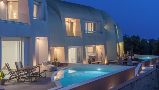 Una casa moderna con una piscina grande, mobiliario exterior y amplias ventanas.