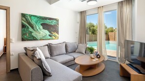 Una sala de estar moderna con un sofá modular, una mesa de centro redonda, un televisor de pantalla plana y un cuadro abstracto grande.