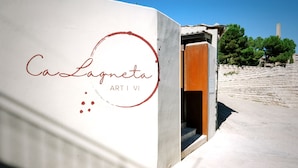 A building with a sign reading "Caslagnetta ART I VI" and a stone wall in the background. - Hotel Boutique CaLagneta - Art i vi (Cervera)