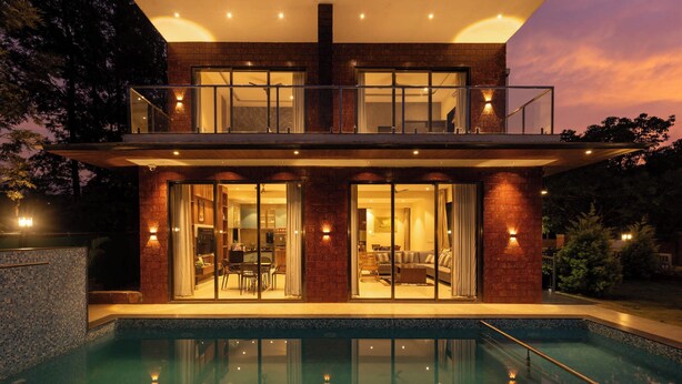 A modern two-story house with a swimming pool, large glass doors, and a balcony. - Brick and beam (Mahabaleshwar)
