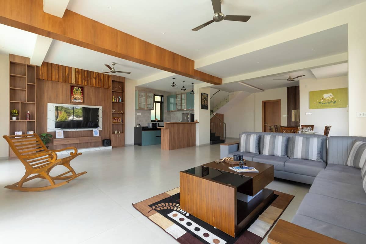 A spacious living area with a wooden ceiling, a sofa, a coffee table, and a TV.