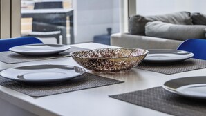 Una mesa de comedor con platos, un cuenco decorativo y vistas de un edificio a través de una ventana.