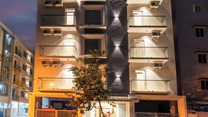 A multi-story hotel with balconies, air conditioning units, and a central vertical feature. - Hotel Rivido Near Manyata Tech park (Bengaluru)