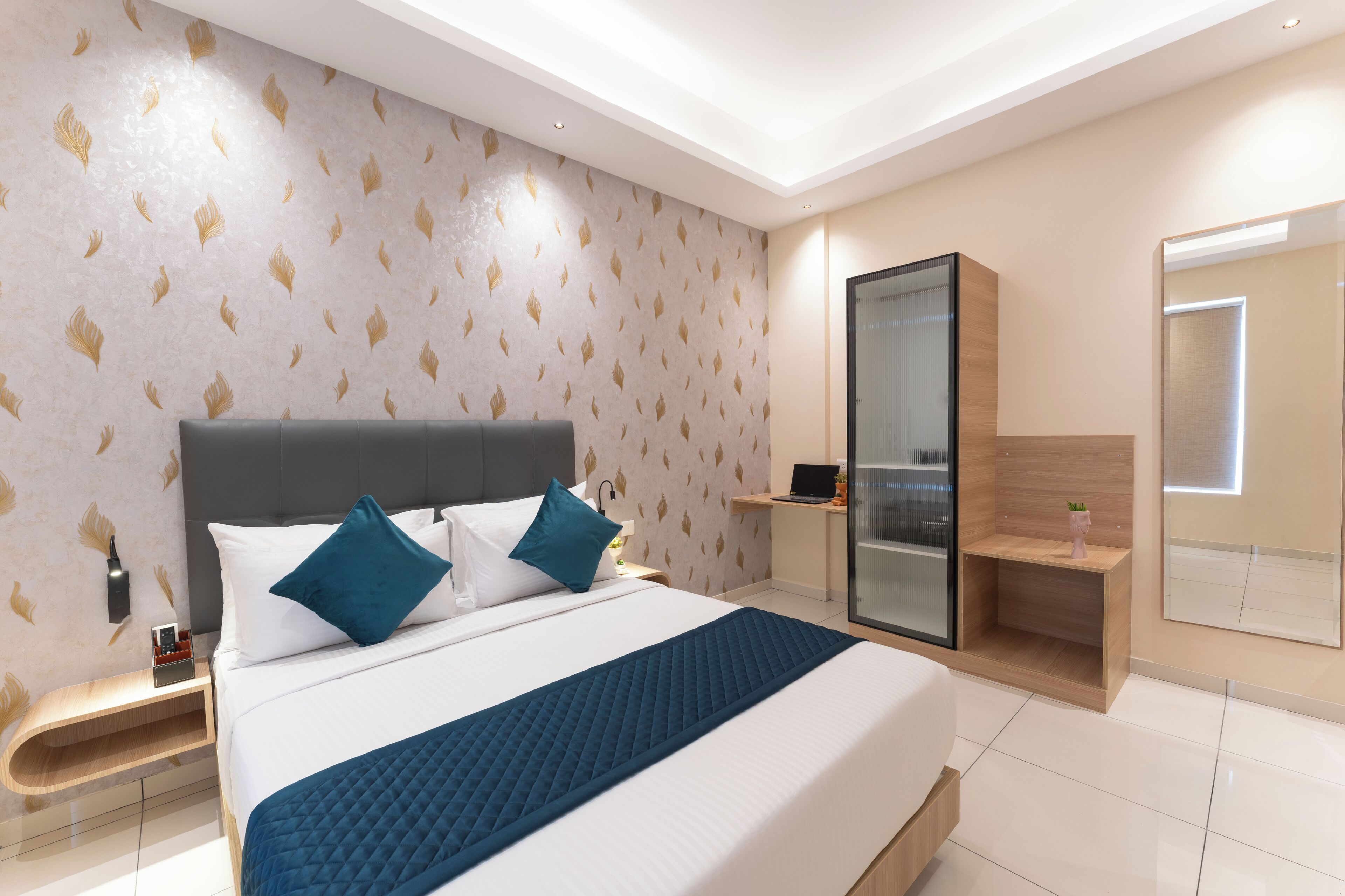 Una habitación de hotel moderna con una cama grande, una mesita de noche, un escritorio y una zona de ducha con paredes de cristal.