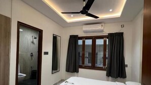 Une chambre d’hôtel moderne, équipée d’un lit, d’un ventilateur de plafond et offrant une vue sur la ville par la fenêtre.