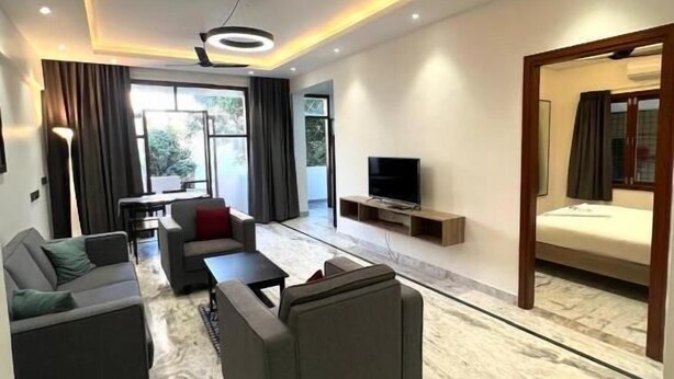 Un salon moderne doté d’un ventilateur de plafond, d’un téléviseur à écran plat et d’un ensemble de canapés.