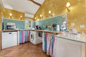 Cocina con lavadora, microondas y horno, además de un salpicadero de azulejos y paredes doradas.
