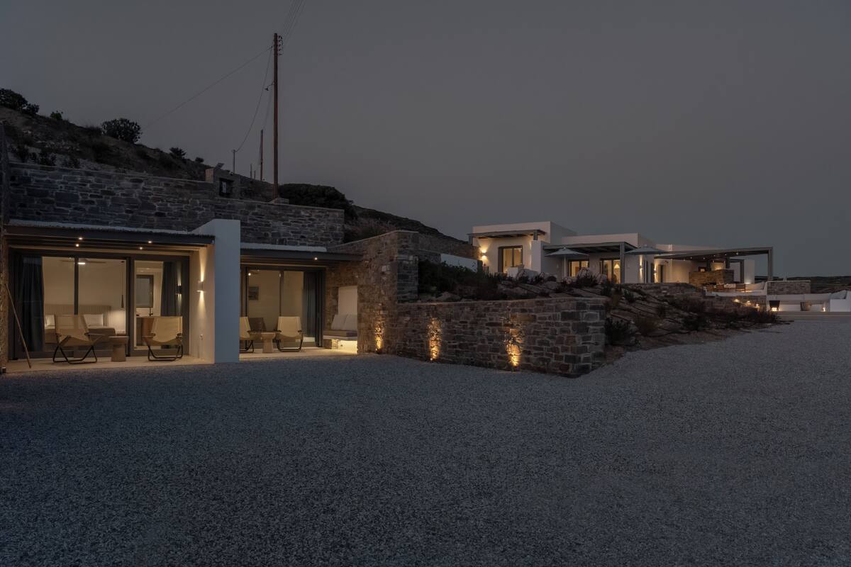 A modern house with a stone facade, a gravel driveway, and outdoor seating.