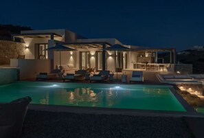 A modern villa with a swimming pool, outdoor seating, and a well-lit patio area. - Avera Luxury Private Villas (Paros)