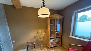 Ein Zimmer mit Holzboden, einem roten Sessel, einem Holzschrank und einer Pendelleuchte.