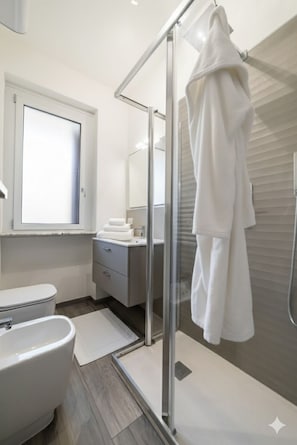 Une salle de bain moderne avec une douche à parois de verre, des toilettes et un meuble-lavabo avec un miroir.