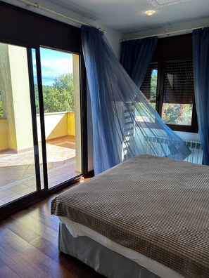 Une chambre avec un lit, une porte-fenêtre coulissante et une vue sur l’extérieur.