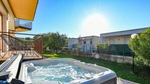 A hot tub with a wooden deck, a balcony, and a clear sky. - MGH- Dajaami Apartment Lazise (Lazise)