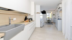 A modern kitchen with a large sink, white cabinets, and a wooden countertop. - MGH- Dajaami Apartment Lazise (Lazise)