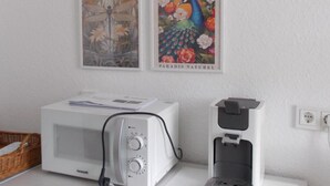 Una cocina con microondas, cafetera y cuatro carteles con motivos botánicos en la pared.