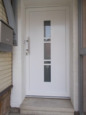 A white door with a vertical window, a mailbox, and a concrete step leading to the entrance. - Nature and Tranquility Surrounded by Gentle Hills and Evergreen Fields – Perfect for Peace Seekers (Uslar)