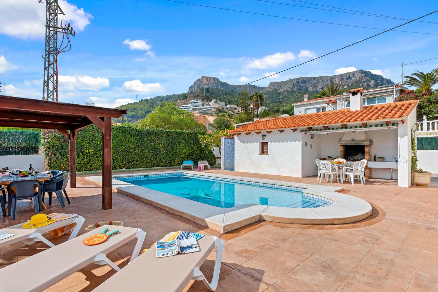 A residential property with a swimming pool, outdoor seating, and a view of mountains.
