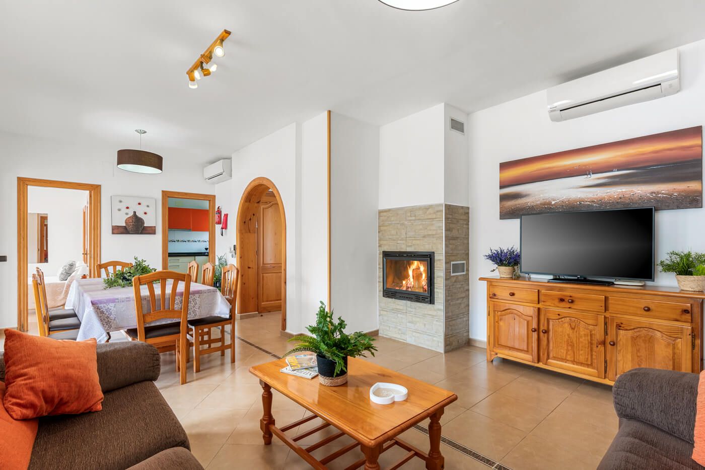 A living room with a fireplace, a television, and a dining area with a table and chairs.