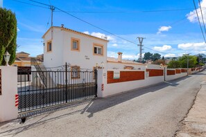 A gated property with a white building, a metal gate, and a brick wall. - Villa Mercedes - Plusholidays (Calpe)