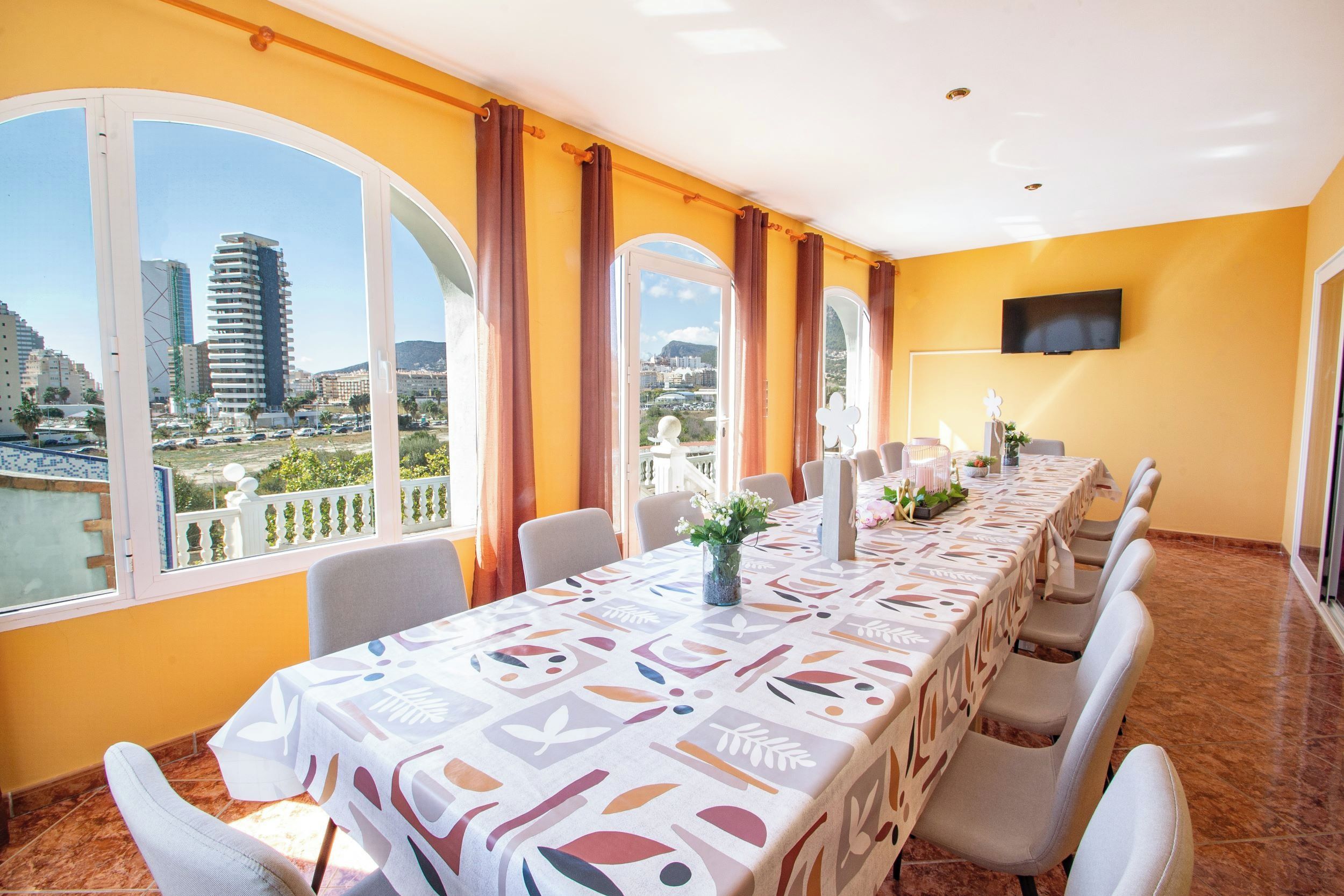 A conference room with a long table, chairs, and a city view through large windows.