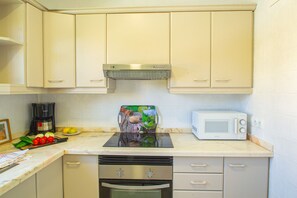 A kitchen with white cabinets, a microwave, a coffee maker, and a digital scale. - Villa Cohete - Plusholidays (Calpe)