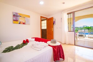 A hotel room with a bed, a red towel, a hat, and a painting on the wall. - Villa Cohete - Plusholidays (Calpe)