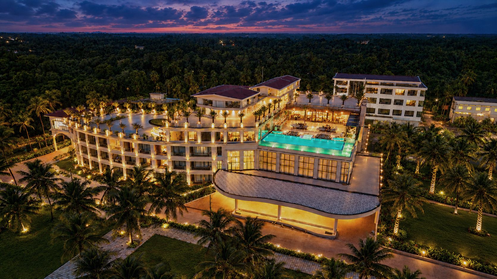 A resort with multiple buildings, a swimming pool, and palm trees.