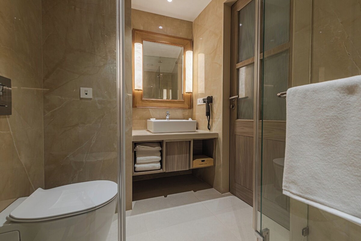 A modern bathroom with a glass shower enclosure, a white sink, and a wooden vanity.