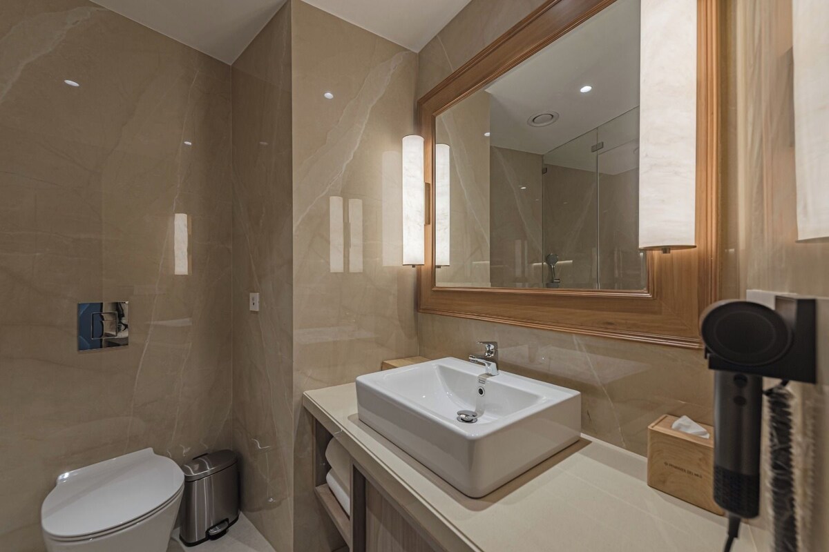 A modern bathroom with a large mirror, a sink, and a toilet.